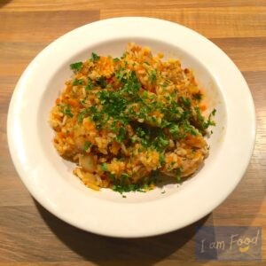 Foto van een bord met rijst, vlees, uien en peentjes (Plov)